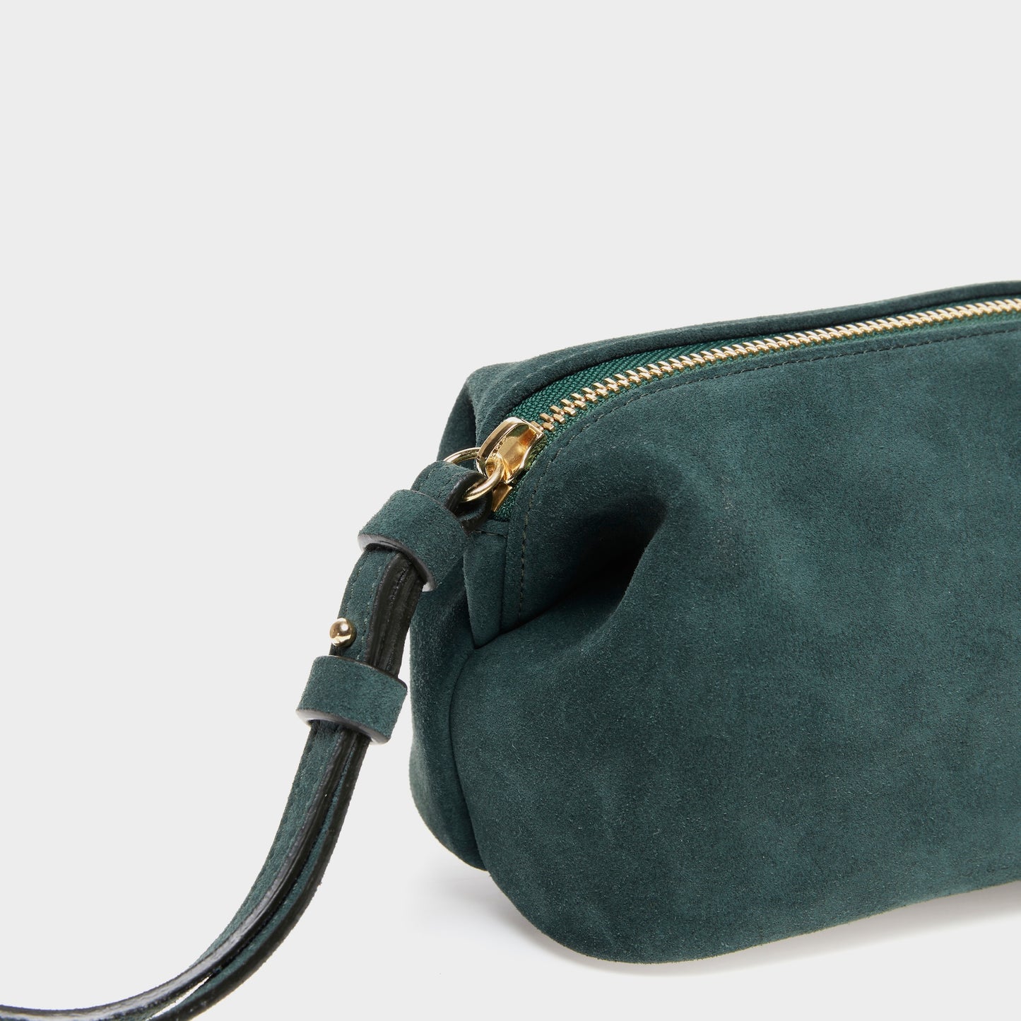 Close-up of soft suede texture and gold zipper on mini pouch