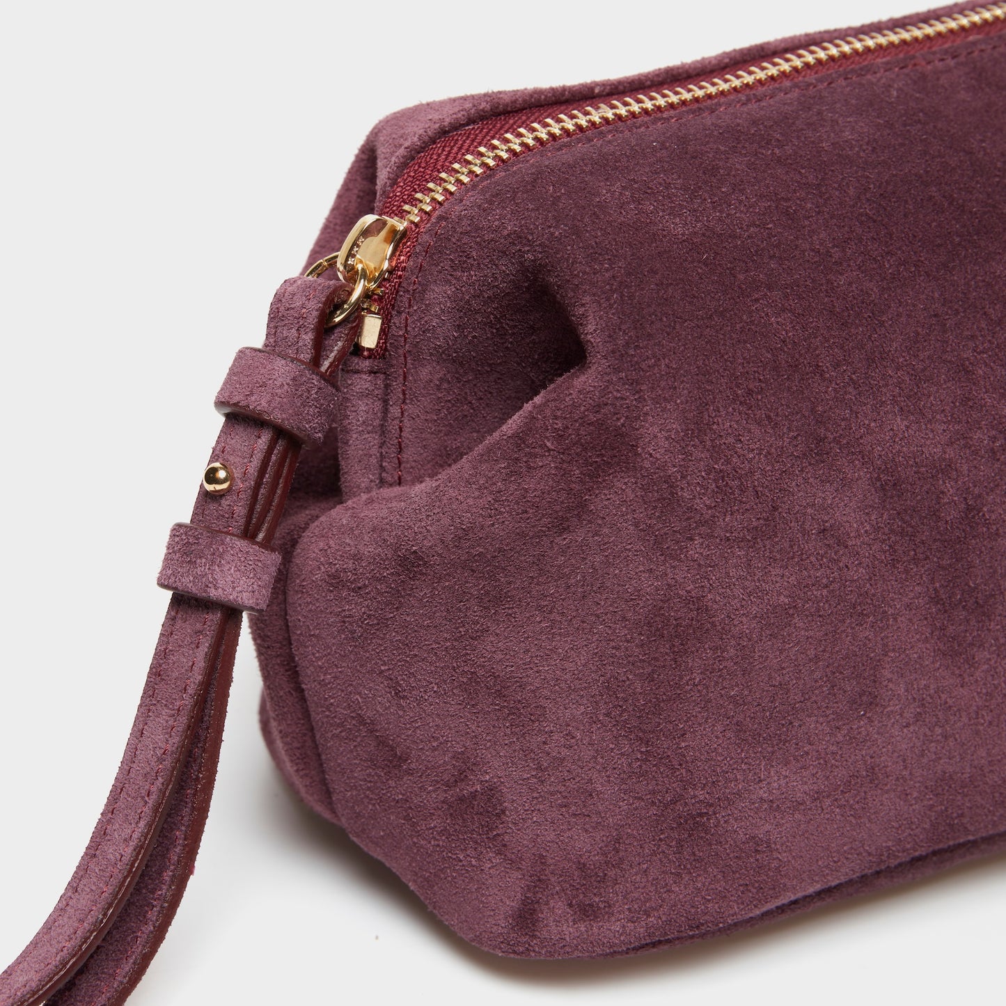 Close-up of soft suede texture and gold zipper on mini pouch