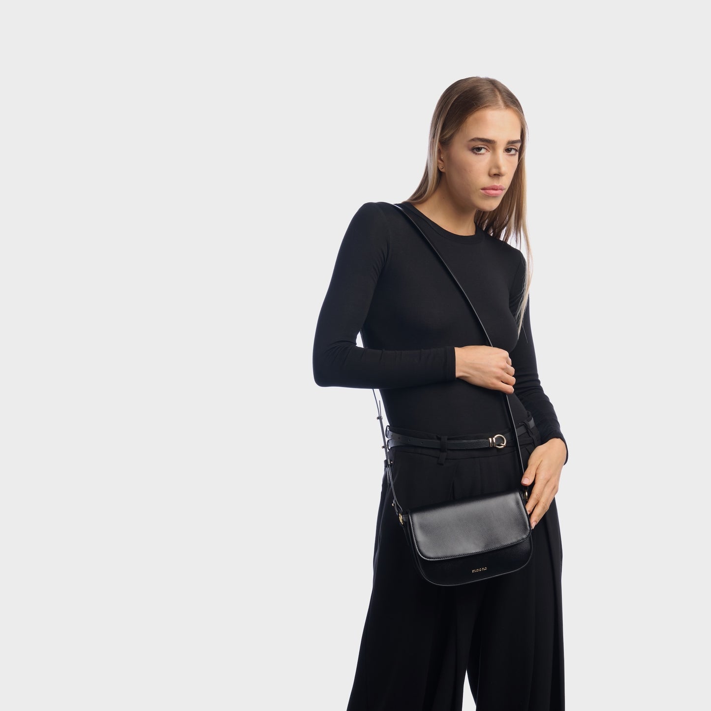 Woman wearing taupe mini leather crossbody bag with minimalist design