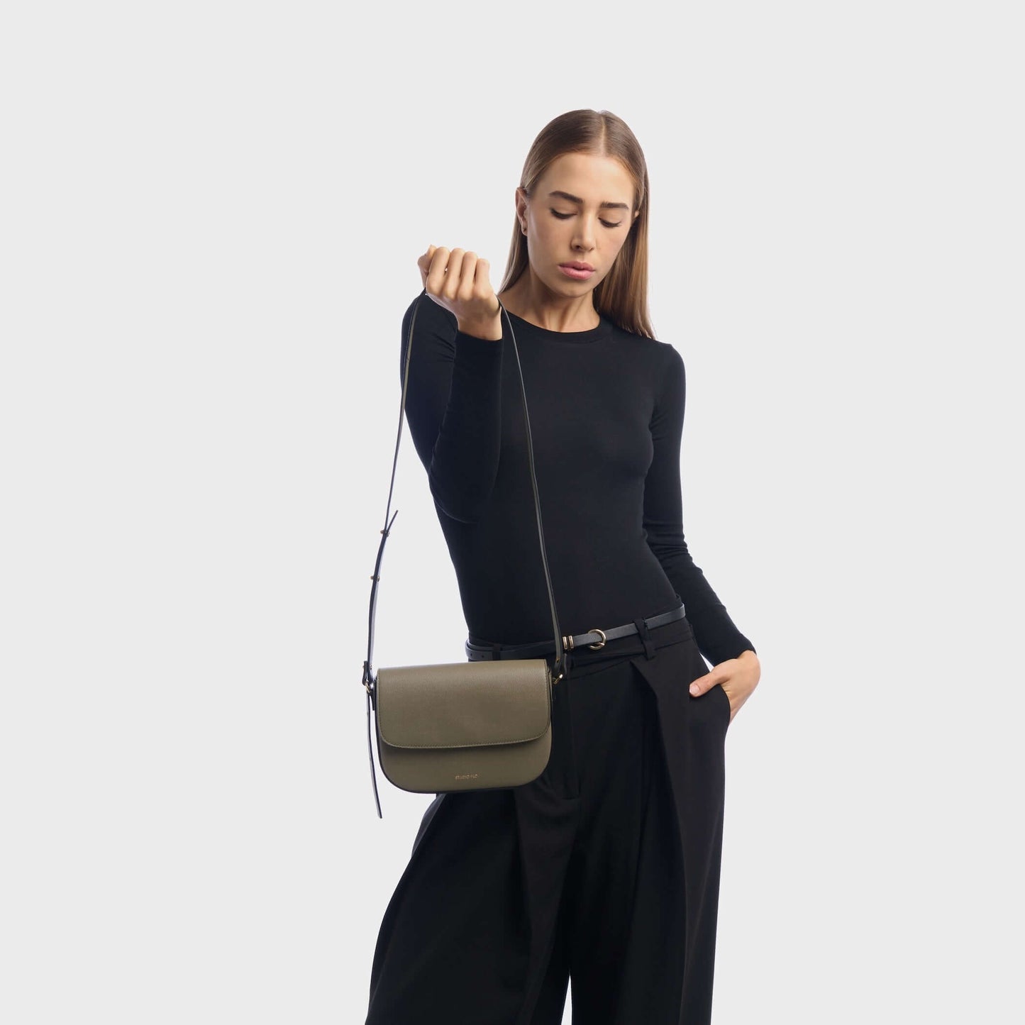 Woman wearing taupe mini leather crossbody bag with minimalist design