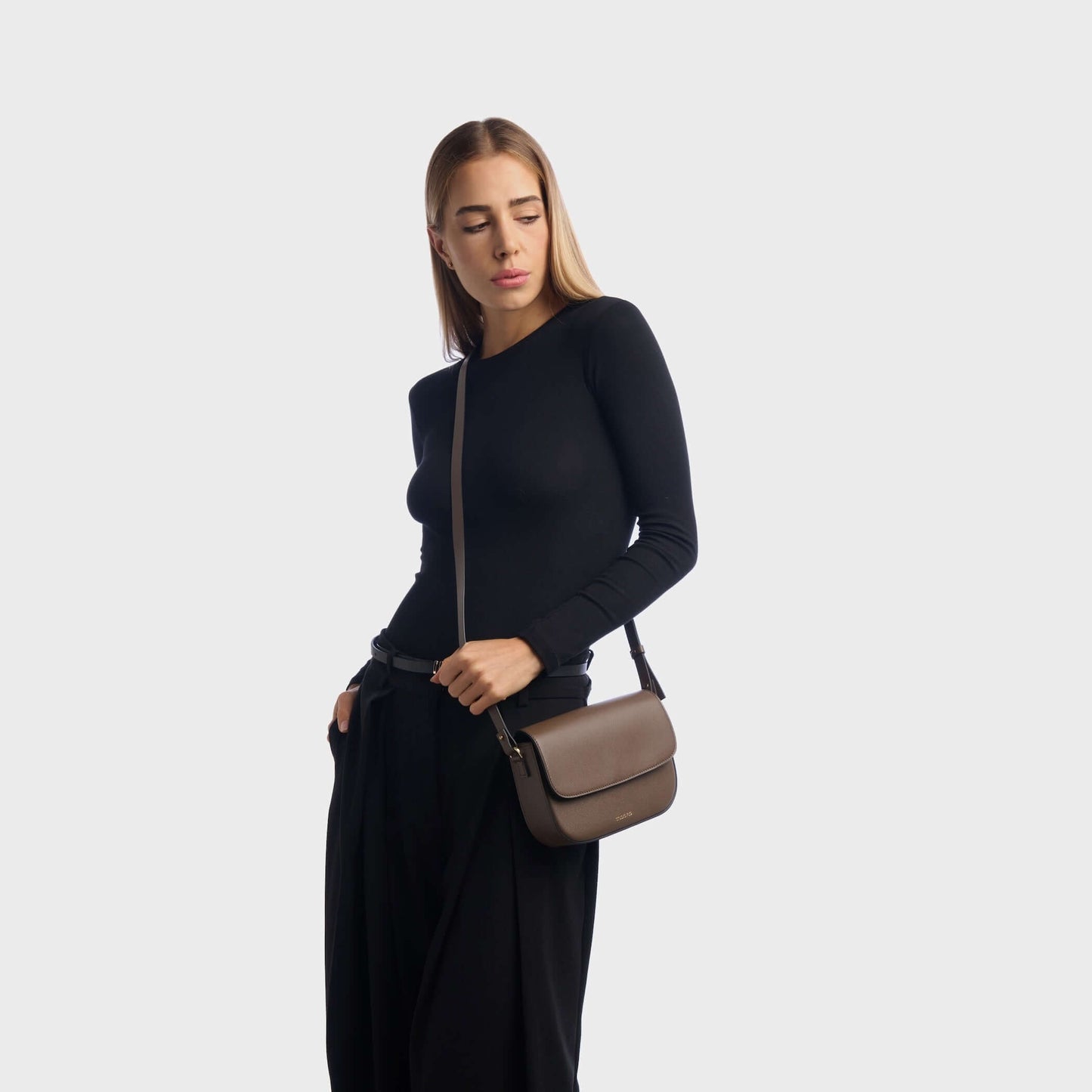 Woman wearing taupe mini leather crossbody bag with minimalist design