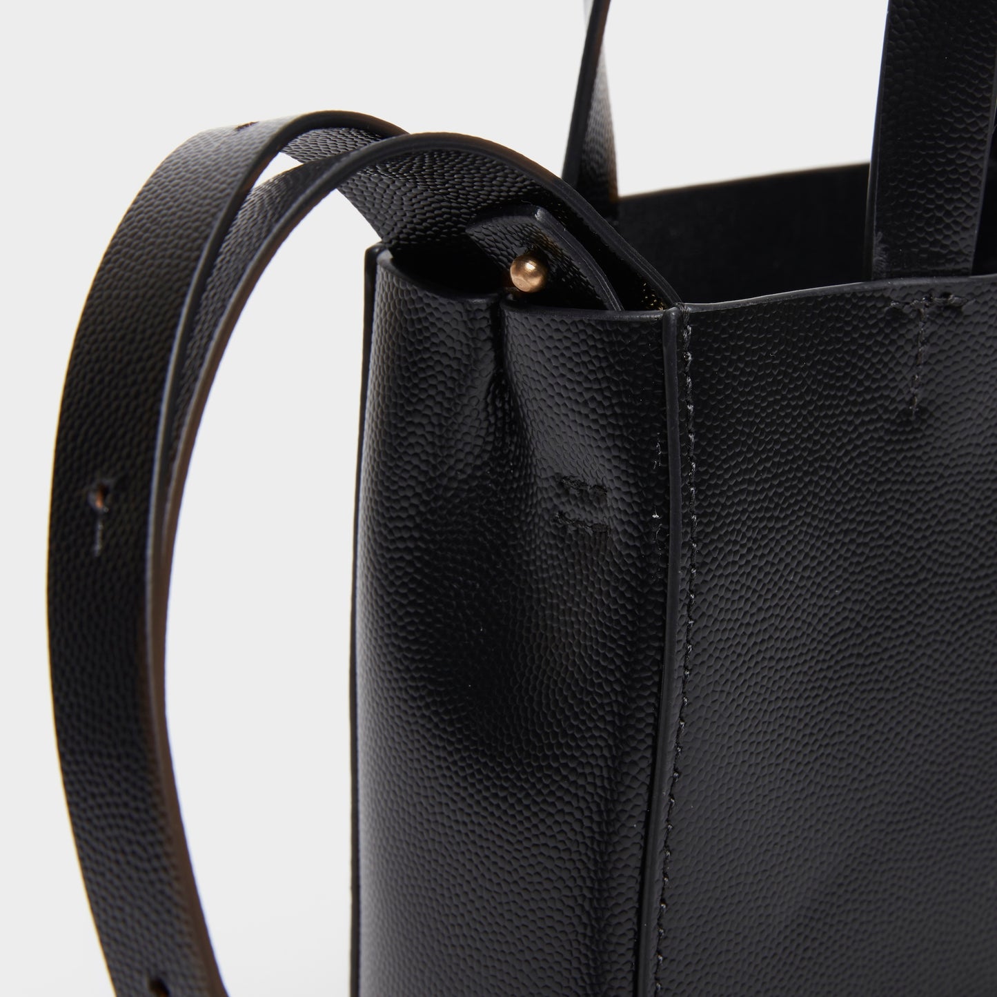 Close-up of leather texture and stitching on black mini handbag