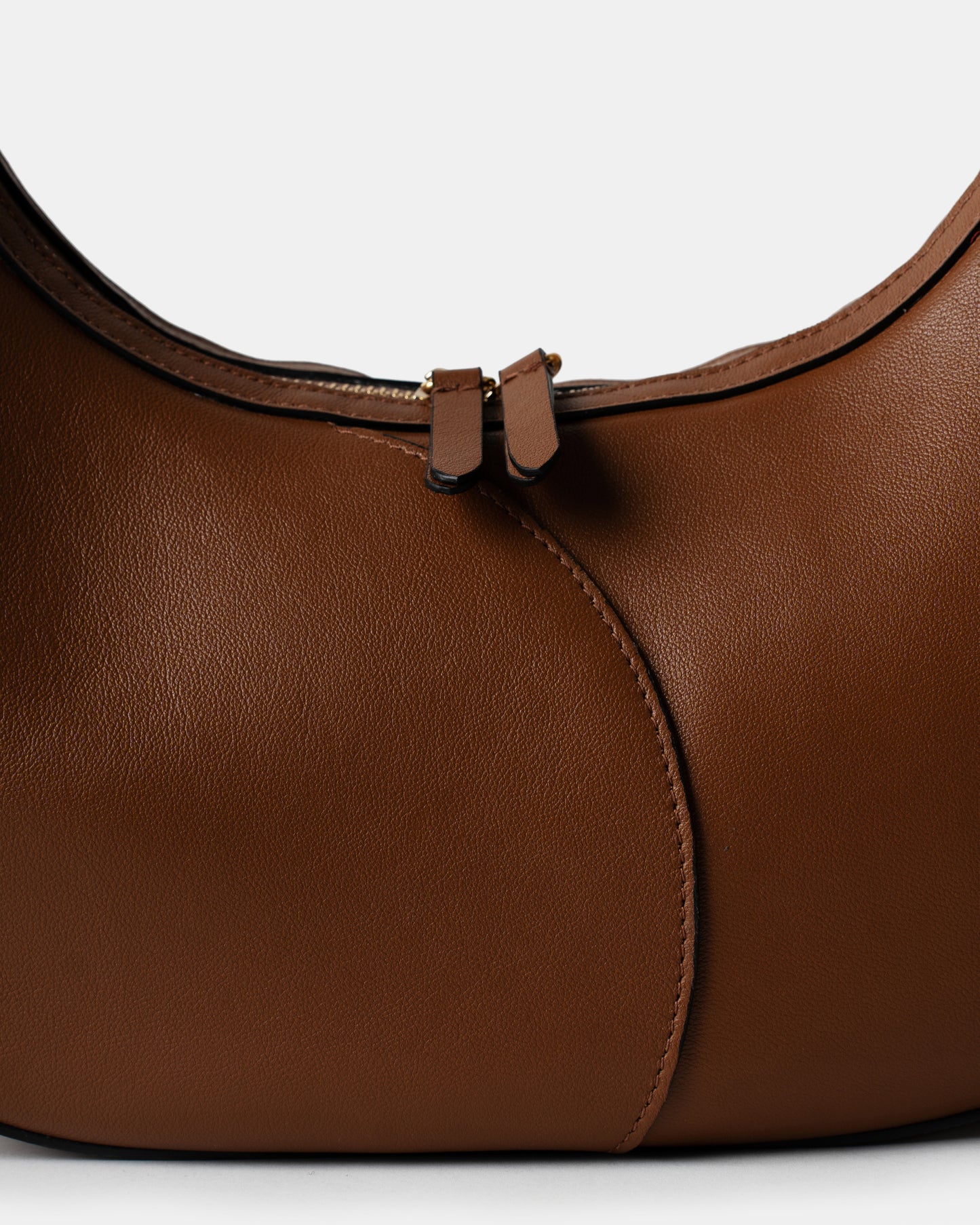 Detail of smooth cognac leather and stitching on big crescent bag