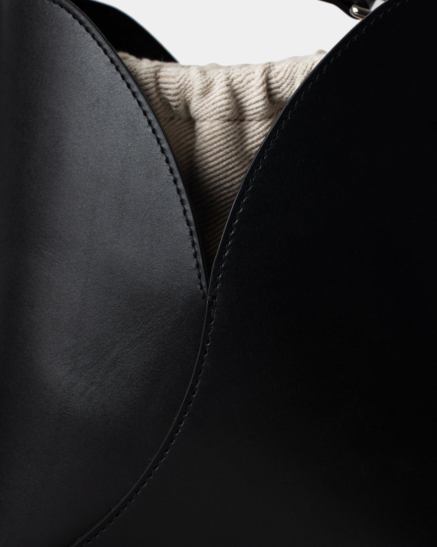 Close-up of stitching and logo on black calfskin leather bucket bag