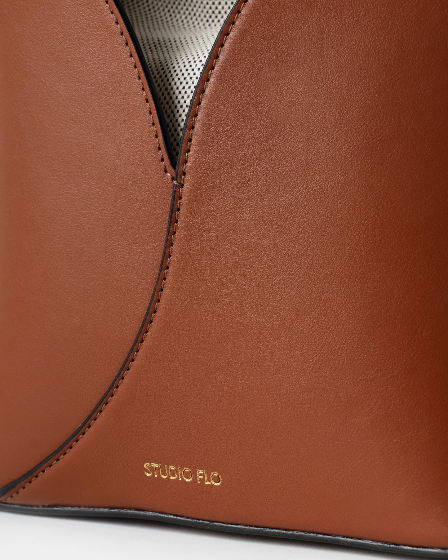 Close-up of stitching and gold logo on smooth calfskin bucket bag