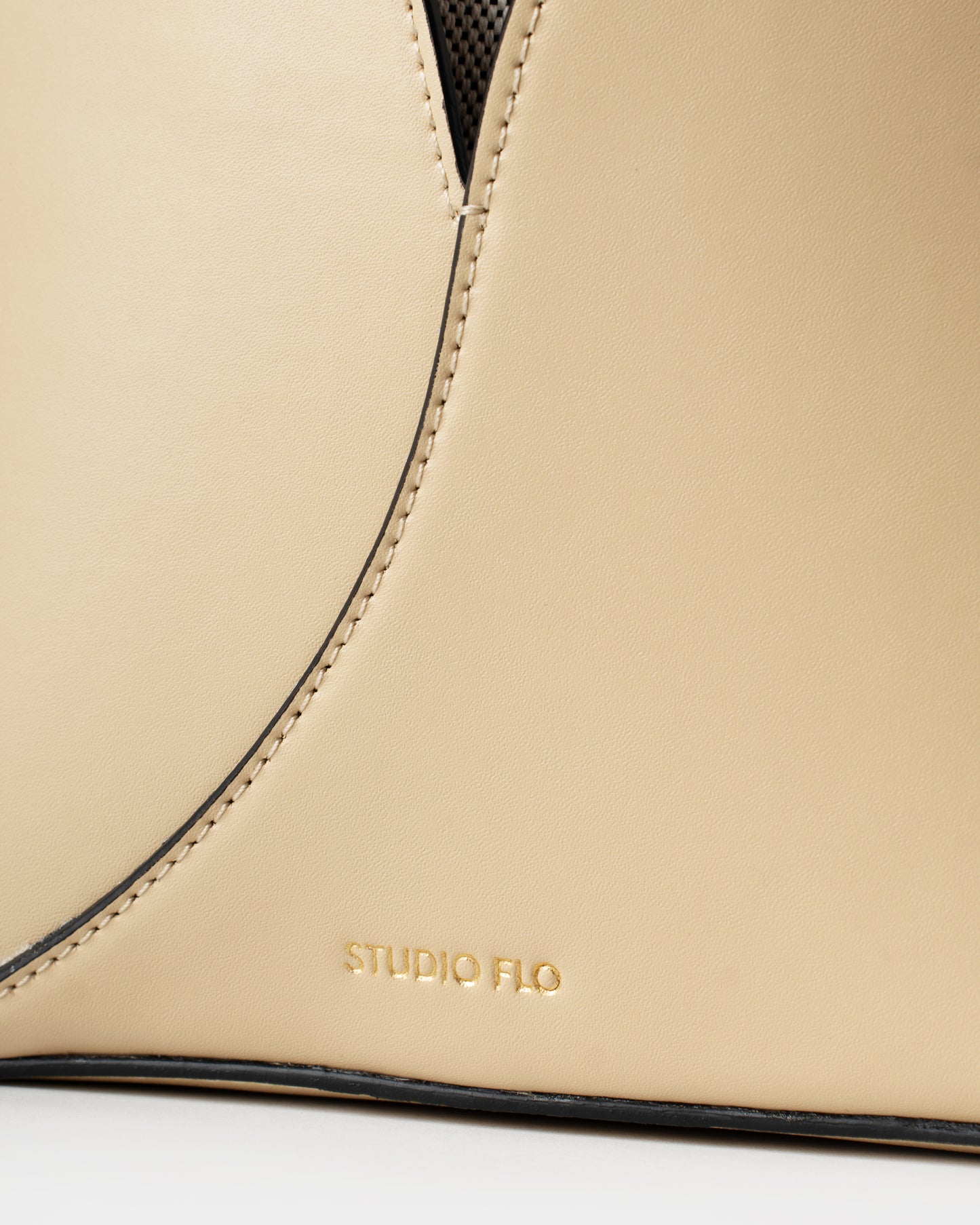 Close-up of stitching and gold logo on smooth cream calfskin bucket bag