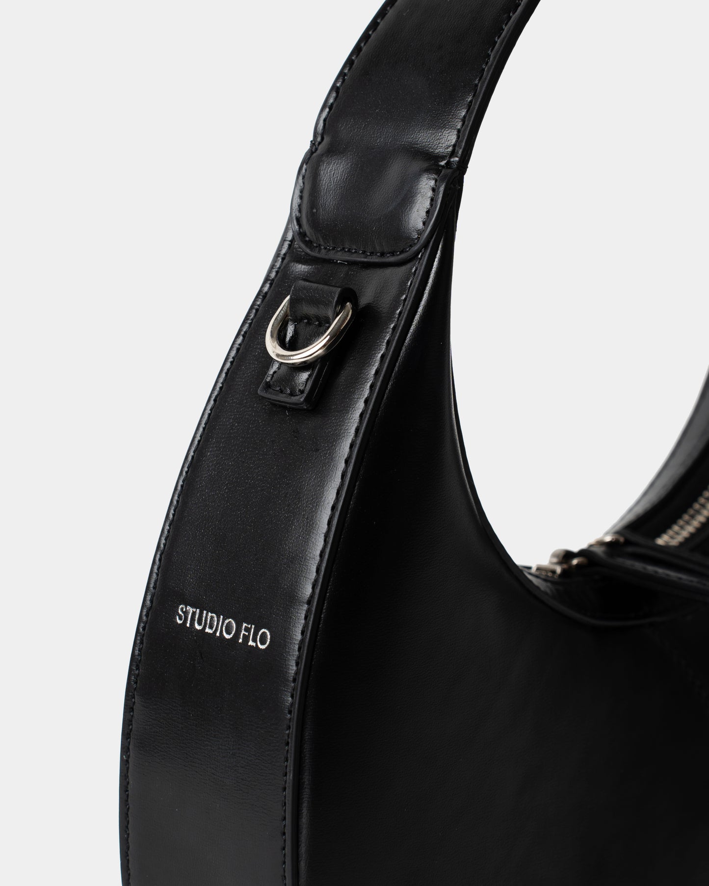 Detail of smooth black leather and stitching on mini crescent bag