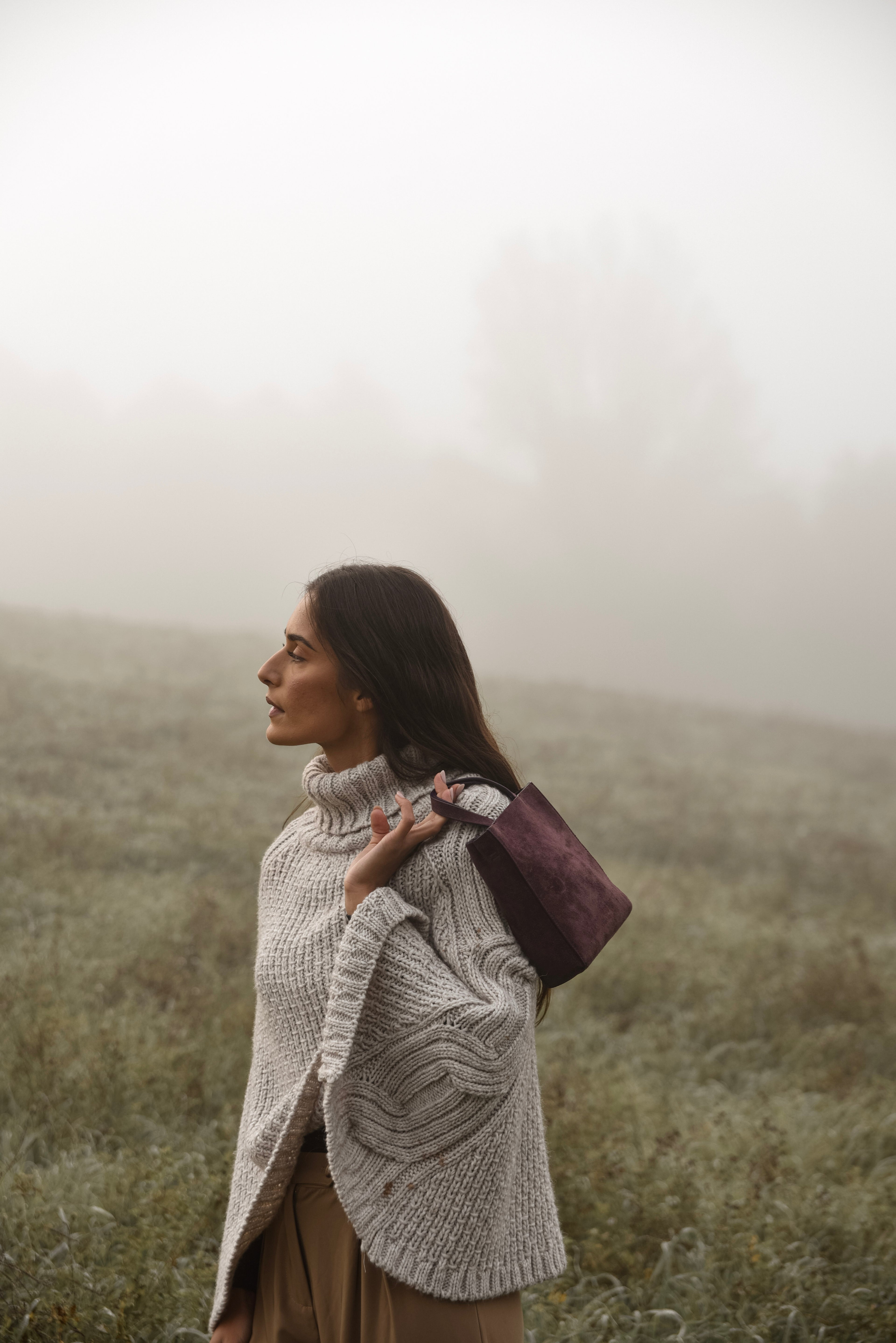Woman in a knit sweater standing in a foggy field