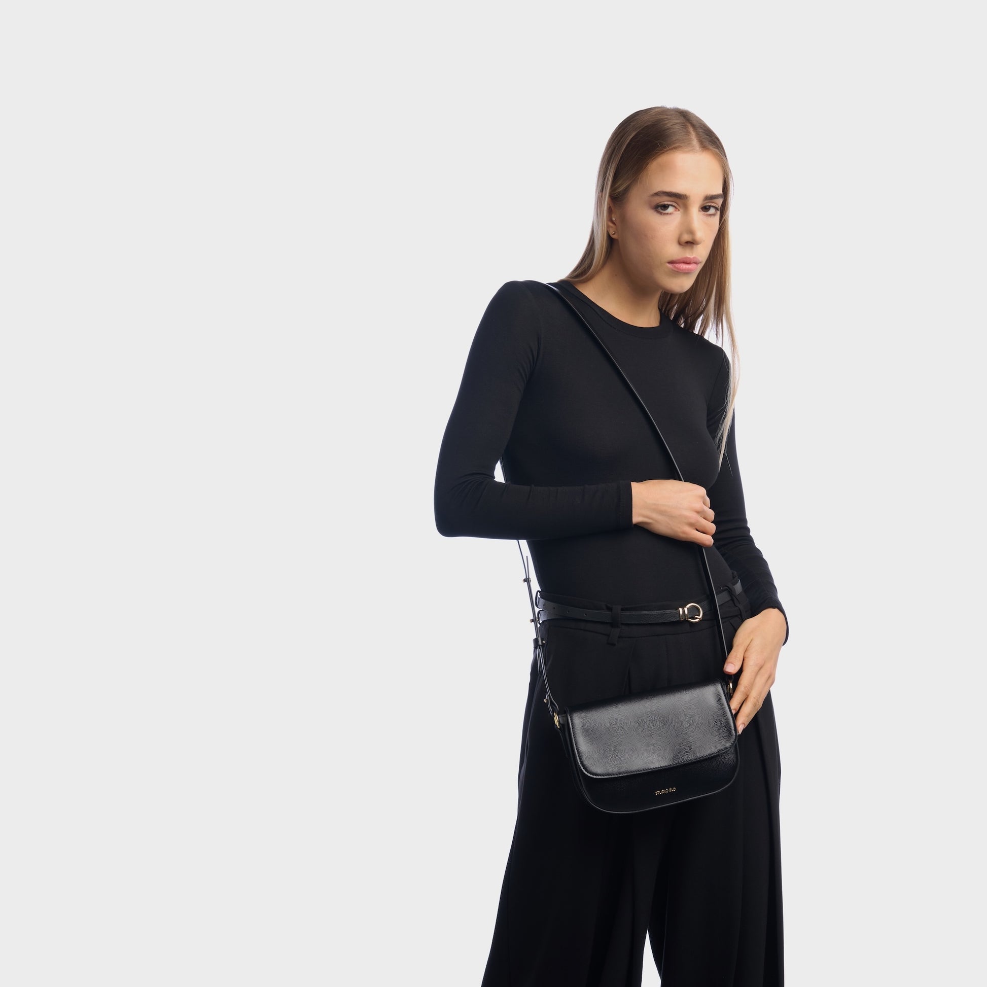 Woman wearing taupe mini leather crossbody bag with minimalist design