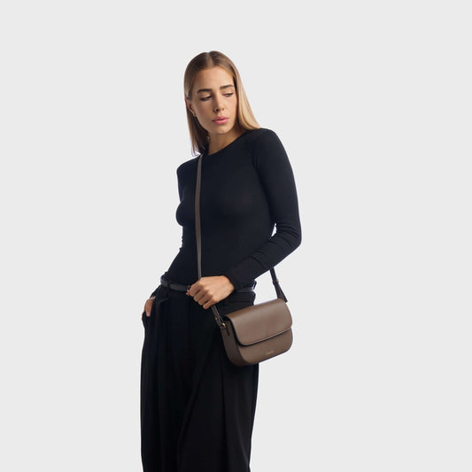 Woman wearing taupe mini leather crossbody bag with minimalist design