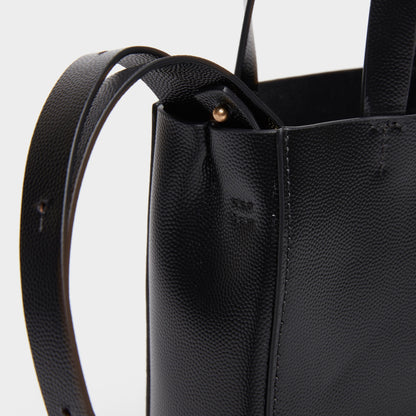Close-up of leather texture and stitching on black mini handbag