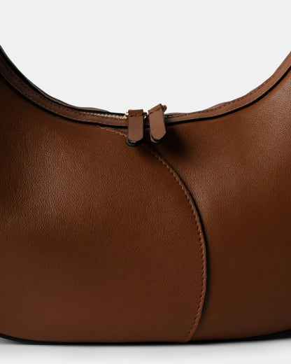 Detail of smooth cognac leather and stitching on big crescent bag