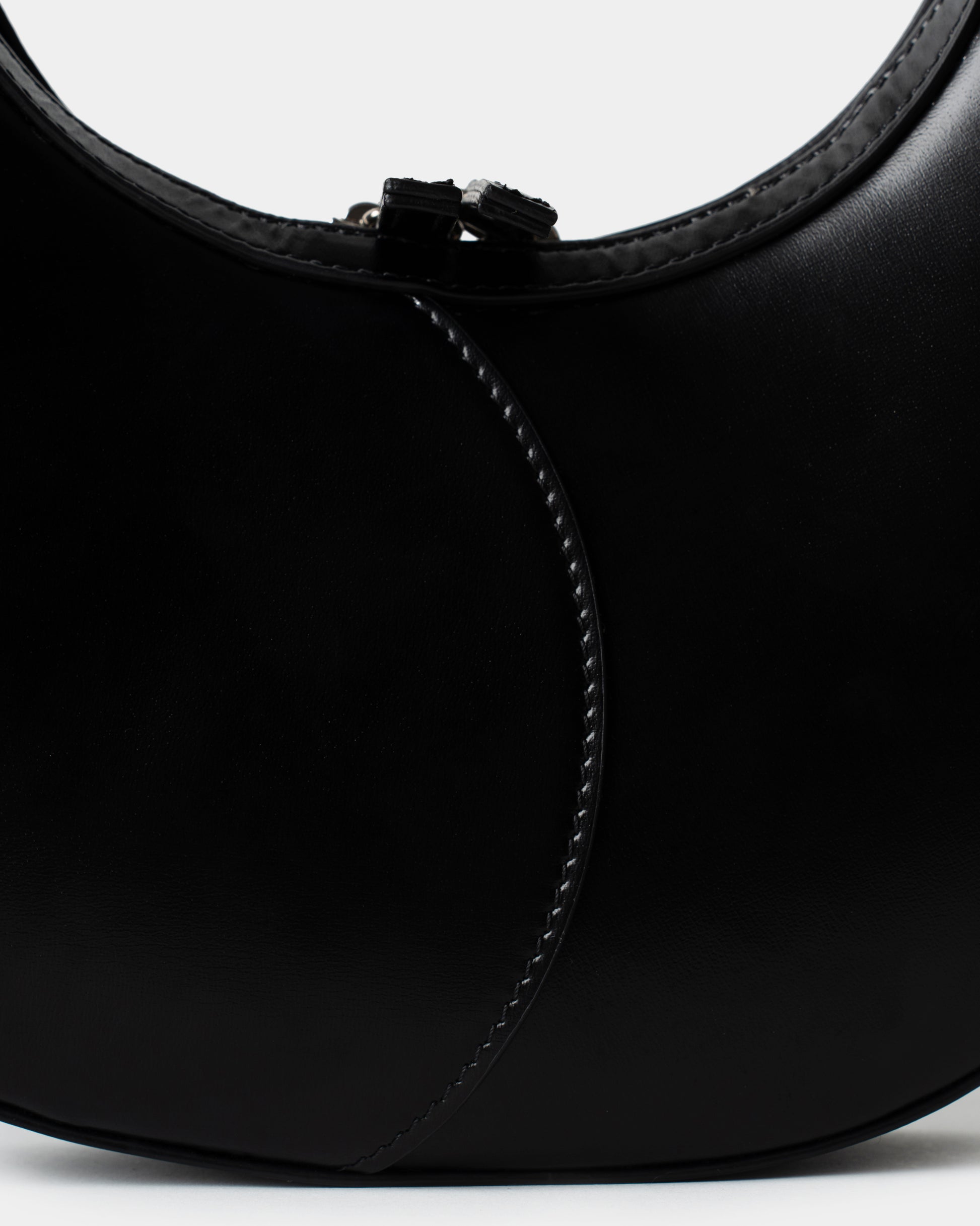 Black leather moon bag with contrast curved stitching and zip closure