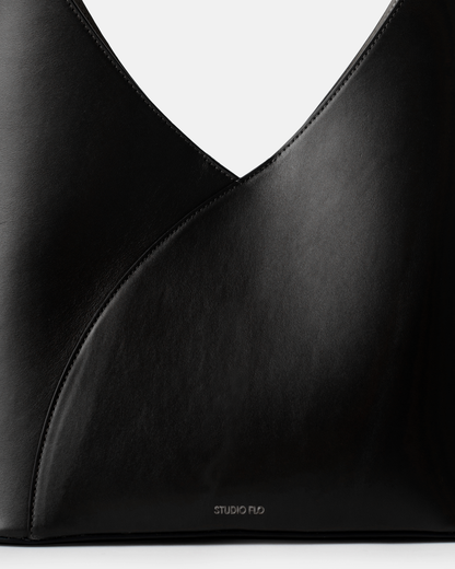 Close-up of structured leather handle on sculptural black bag