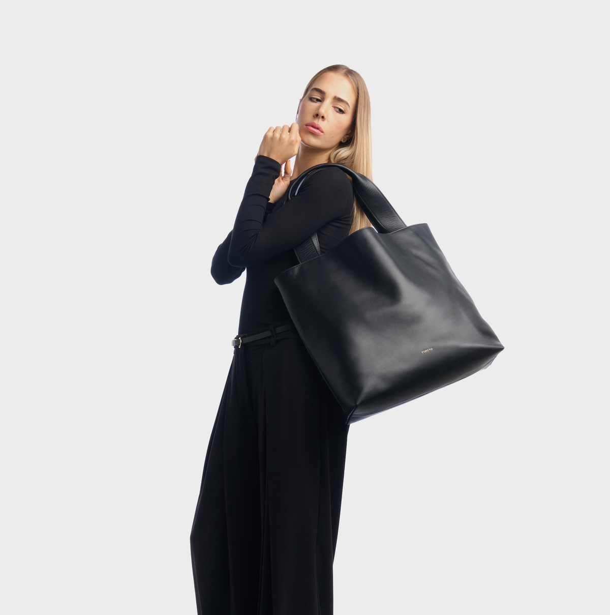 Model wearing the Urban Tote black leather bag on her shoulder with a black outfit